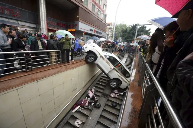 People look on as a car is stuck after falling into a stairs of an underpass, in Fuzhou, Fujian province, China, December 9, 2015. The driver, surnamed Yang, in her 30s, backed the car into the underpass entrance on Wednesday by mistaking the accelerator as the brake. No one was injured during the accident, local media reported. (Photo by Reuters/Stringer)