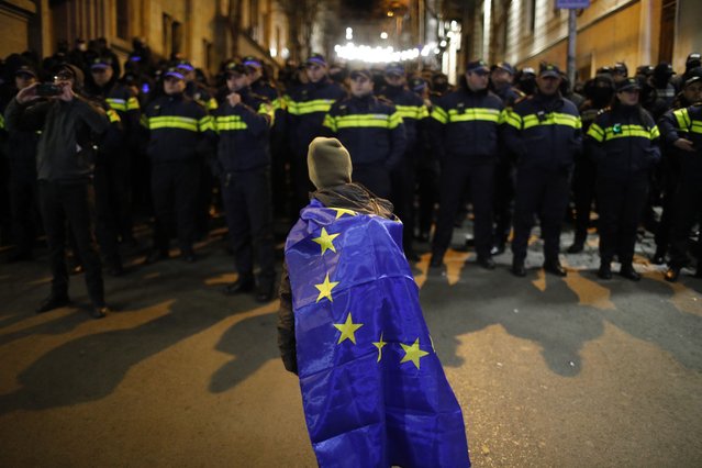  A person wears a European Union flag on their shoulders as they face police while supporters of Georgian opposition parties gather near the Georgian Parliament building to protest against the results of the parliamentary election, in Tbilisi, Georgia, 24 November 2024. The first session of the newly elected Georgian Parliament is scheduled for 25 November, Parliament Chairman Shalva Papuashvili announced. On 26 October parliamentary elections were held in Georgia. Around 20 parties competed for seats in the country's highest legislative body, which consists of 150 deputies. The ruling Georgian Dream Party was announced winner of the parliamentary elections. (Photo by David Mdzinarishvili//EPA/EFE)