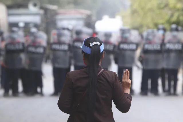 A female protester flashes the three-fingered salute in front of police in Mandalay, Myanmar, Saturday, February 20, 2021. (Photo by AP Photo/Stringer)