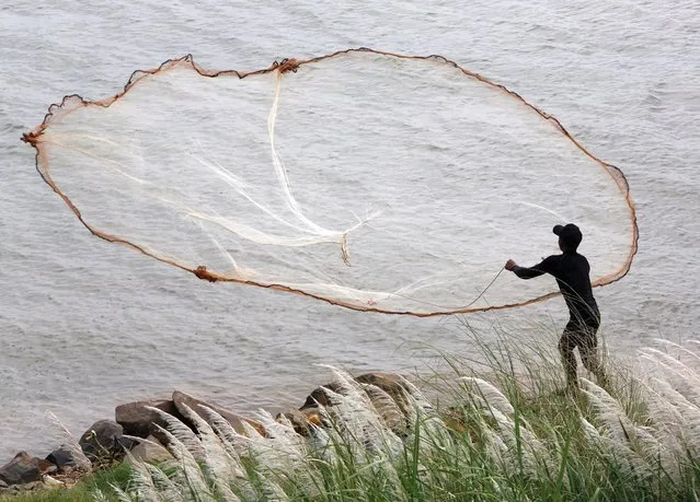 A man casts a net on the Mekong River in Phnom Penh, Cambodia, 24 February 2021. The inter-governmental Mekong River Commission (MRC) has expressed concerns over the declining water levels in the Mekong River, partially due to outflaw restrictions from upstream Chinese dams, an attribution China has disputed. (Photo by Kith Serey/EPA/EFE)