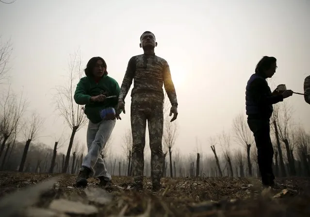 A staff paints a model with camouflage colours to blend him in with the background for Chinese artist Liu Bolin's artwork “Dongji”, or Winter Solstice, on the second day after China's capital Beijing issued its second ever “red alert” for air pollution, in Beijing, China, December 20, 2015. In this artwork, Liu wants to express his concerns about China and its people, including air pollution problem, Liu told Reuters. (Photo by Kim Kyung-Hoon/Reuters)