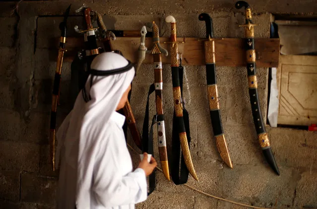 A Palestinian man looks at swords made by 45-year-old blacksmith Mueen Abu Wadi, who inherited the job from his father and grandfather, at a workshop in Gaza City November 14, 2016. (Photo by Suhaib Salem/Reuters)