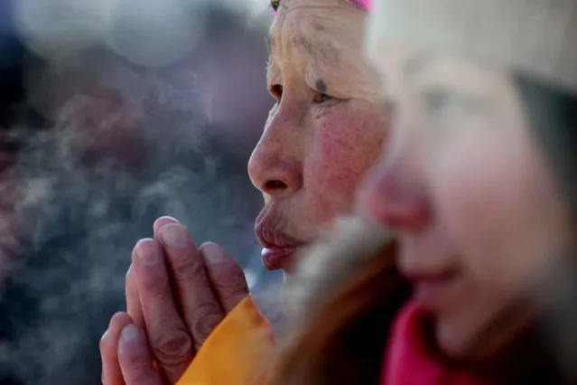 A woman listens as the Dalai Lama (L) speaks to worshippers in minus 20 degrees Celcius temperatures at the Gandantegchilen monastery in Ulan Bator, the capital of Mongolia, on November 19, 2016. The Dalai Lama met with Buddhist worshippers on November 19 during a four- day visit to Mongolia, despite Beijing' s strident demand that he be barred from entering the country. (Photo by Byambasuren Byamba-Ochir/AFP Photo)
