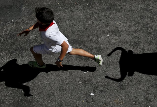 A boy is chased by a toy bull as he takes part in the Encierro Txiki (Little Bull Run) during the San Fermin festival in Pamplona, northern Spain, July 13, 2015. (Photo by Susana Vera/Reuters)