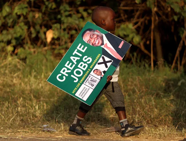 A boy carries a ZANU PF campaign poster after attending the final rally at the National Sports Stadium in Harare, Zimbabwe, July 28, 2018. (Photo by Philimon Bulawayo/Reuters)