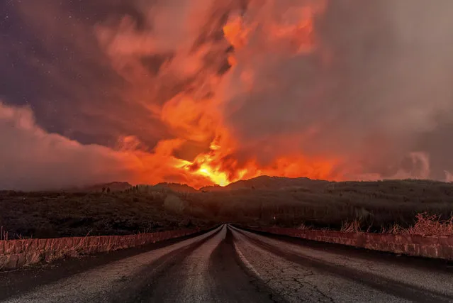 A glowing river of lava gushes from the slopes of Mt Etna, Europe's largest active volcano, near Zafferana Etnea, Sicily, early Wednesday, March 10, 2021. Today's activity is the 11th major eruption in the past few weeks. (Photo by Salvatore Allegra/AP Photo)