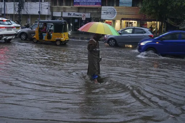A traffic police officer tries to clear water logging in a street during rain in Hyderabad, India, Thursday, July 20, 2023. India receives its monsoon rains from June to October. (Photo by Mahesh Kumar A./AP Photo)