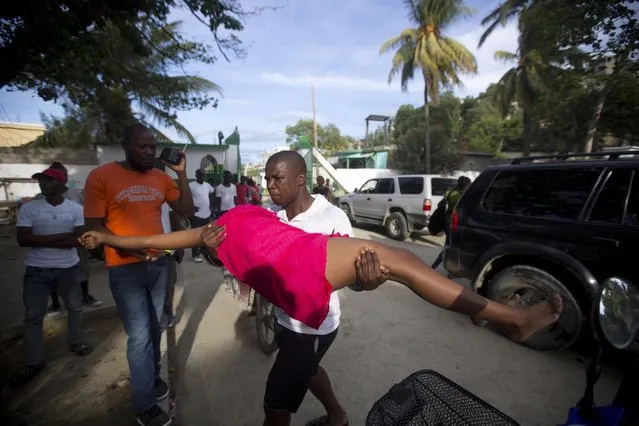 A woman overcome by emotion after an aftershock hit the area, is carried by a relative to the general hospital in Port-de-Paix, Haiti, Sunday, October 7, 2018. A magnitude 5.2 aftershock struck Haiti on Sunday, even as survivors of the previous day's temblor were sifting through the rubble of their cinderblock homes. The death toll stood at 12, with fears it could rise. (Photo by Dieu Nalio Chery/AP Photo)