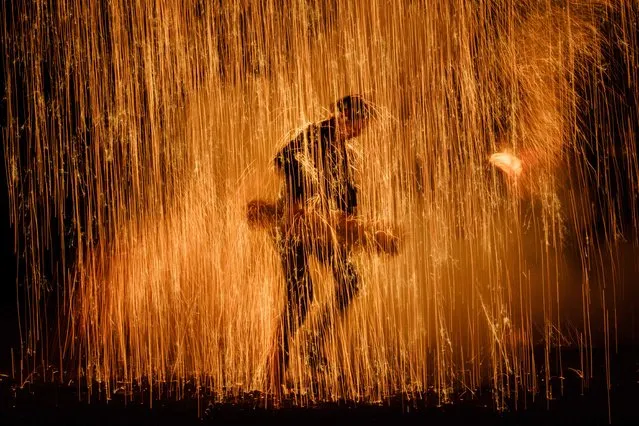 This picture taken on July 20, 2018 shows a man holding his handmade Tezutsu hanabi (handheld fireworks) dedicated to the Yoshida Shrine as a part of a Shinto ritual, on the eve of the Toyohashi Gion festival, in Toyohashi, central Japan. Every year, each male member of the shrine makes his own set of fireworks from bamboo covered by straw ropes with a loaded gun and metal powder, in a tradition that has been practiced for more than 350 years, according to an old document at the shrine. (Photo by Yasuyoshi Chiba/AFP Photo)