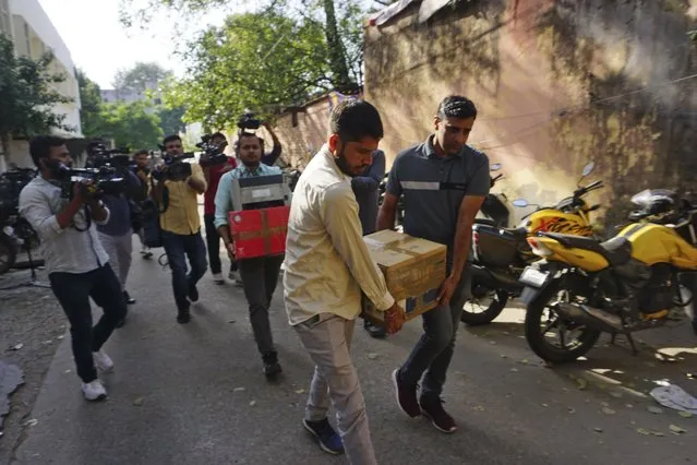 Security officers carry boxes of material confiscated after a raid at the office of NewsClick in New Delhi, India, Tuesday, October 3, 2023. Indian police raided the offices of the news website that's under investigation for allegedly receiving funds from China, as well as the homes of several of its journalists, in what critics described as an attack on one of India's few remaining independent news outlets. (Photo by Dinesh Joshi/AP Photo)