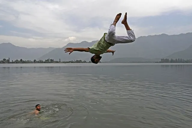 A boy jumps in the waters of Dal Lake on a hot summer day in Srinagar on June 11, 2021. (Photo by Tauseef Mustafa/AFP Photo)