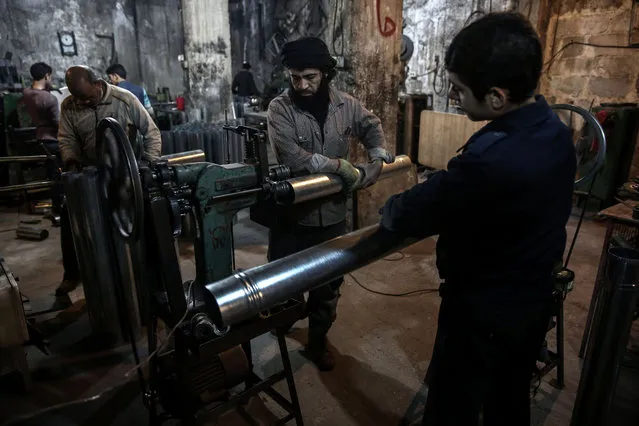 Syrians work at a factory making wood-burning stoves in the rebel-held town of Douma, on the eastern outskirts of Damascus on December 19, 2016. As the weather in Douma is getting colder, wood is the most affordable source of heating for residents. (Photo by Sameer Al-Doumy/AFP Photo)