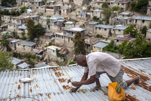 Antony Exilien secures the roof of his house in response to Tropical Storm Elsa, in Port-au-Prince, Haiti, Saturday, July 3, 2021. Elsa brushed past Haiti and the Dominican Republic on Saturday and threatened to unleash flooding and landslides before taking aim at Cuba and Florida. (Photo by Joseph Odelyn/AP Photo)