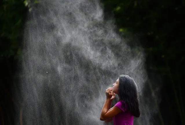 Scarlett Zelaya, 10, of Woodbridge, VA cools off under a water mister while visiting the Smithsonian National Zoological Park on Wednesday July 21, 2021 in Washington, DC. (Photo by Matt McClain/The Washington Post)