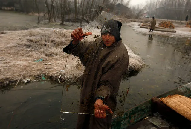 A boy shows a piece of ice that he collected on the partially frozen interiors of Dal lake on a cold winter morning in Srinagar December 26, 2018. (Photo by Danish Ismail/Reuters)