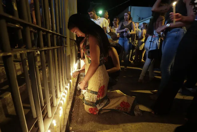 A woman who lost a relative lights candles outside a church after a Mass for the victims of a mine dam collapse in Brumadinho, Brazil, Thursday, January 31, 2019. The dam failure unleashed a surge of mud that buried buildings adjoining the dam and several parts of the nearby city of Brumadinho. (Photo by Andre Penner/AP Photo)
