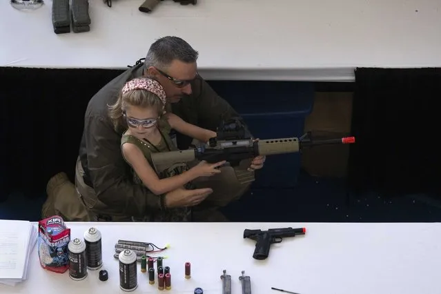 A man shows a girl how to hold an airsoft gun during the NRA Youth Day at the National Rifle Association's annual meeting in Houston, Texas May 5, 2013. (Photo by Adrees Latif /Reuters)