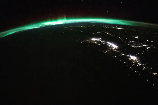 A view of the northern lights above Canada, with the city lights of Vancouver, Seattle, and Portland visible below, captured from the International Space Station, in orbit over the Pacific Ocean, on November 9, 2023. (Photo by NASA)