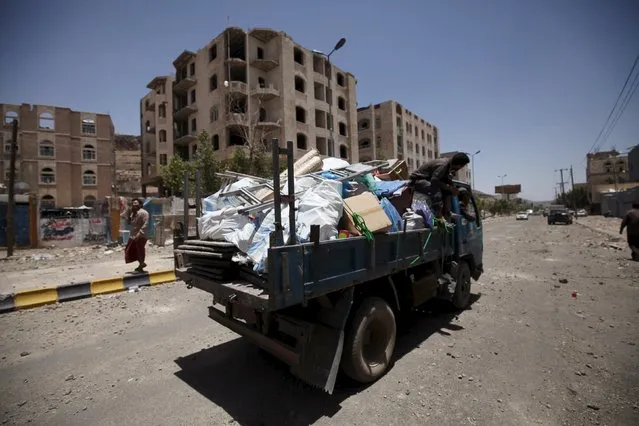 People flee Sanaa with their belongings, fearing renewed air strikes, along a street damaged by an air strike on Monday that hit a nearby army weapons depot, in Sanaa April 21, 2015. (Photo by Mohamed al-Sayaghi/Reuters)