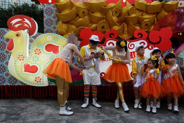 Dancers take part in the upcoming Chinese New Year parade preparing for the rehearsal beside a float from Macau Tourism Office, in Hong Kong, China January 25, 2017. (Photo by Bobby Yip/Reuters)