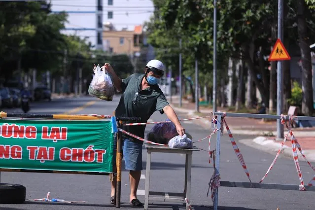 A man picks up food delivery at a checkpoint of a street cordoned off for the lockdown order in Vung Tau, Vietnam Monday, September 6, 2021. (Photo by Hau Dinh/AP Photo)