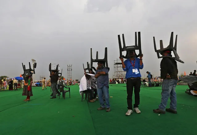 Media personnel and participants cover themselves with chairs as it rains at the venue of the World Culture Festival on the banks of a river in New Delhi, India, March 11, 2016. (Photo by Adnan Abidi/Reuters)