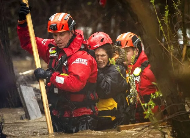 Firefighters rescue a woman from a homeless encampment that became surrounded by floodwater in the Santa Ana River during a rainstorm, Monday, February 5, 2024, in San Bernardino, Calif. (Photo by Ethan Swope/AP Photo)