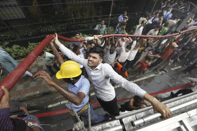 Locals help firefighters douse a fire in a multi-storied office building in Dhaka, Bangladesh, Thursday, March 28, 2019. Fire Department control room official Ershad Hossain said by phone the FR Tower in Dhaka's Banani commercial district caught fire Thursday afternoon and at least 19 fire fighting units joined the operation to douse the blaze and rescue the people trapped inside. (Photo by Mahmud Hossain Opu/AP Photo)