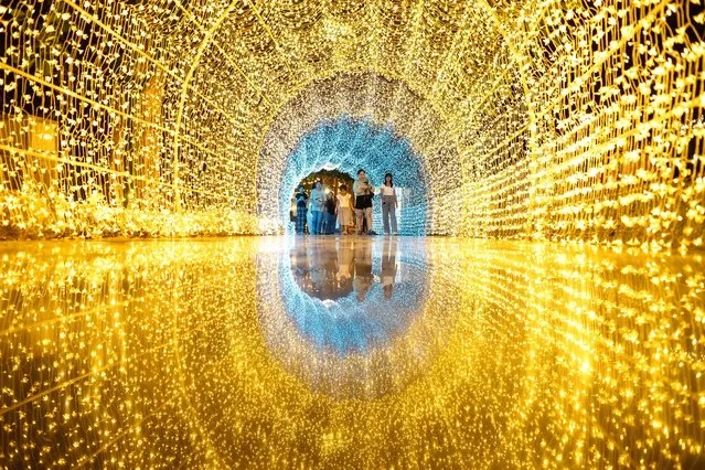 Visitors walk through a tunnel made of light installations at the Nasatta Light festival, in Thailand’s Ratchaburi province on January 13, 2024. (Photo by Manan Vatsyayana/AFP Photo)