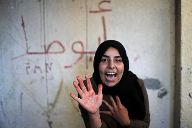 The sister of Palestinian militant Emad Naseer, who was killed in an Israeli air strike, reacts with her hand stained with his blood, during his funeral in the northern Gaza Strip on May 4, 2019. (Photo by Mohammed Salem/Reuters)
