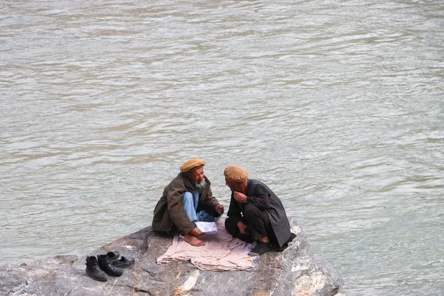 Afghan men sit by the Kokcha river in Fayzabad on March 18, 2024. (Photo by Omer Abrar/AFP Photo)