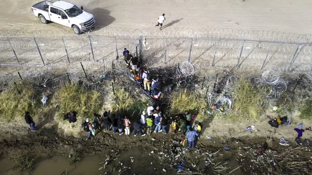 In an aerial view, immigrants pass through coils of razor wire while crossing the U.S.-Mexico border on March 13, 2024 in El Paso, Texas. The wire was placed by the troops as part of Texas Governor Greg Abbott's "Operation Lone Star" to deter migrants from crossing into Texas. The vast majority of immigrants, however, manage to pass through it, and are then permitted to turn themselves in to U.S. Border Patrol agents, usually to request asylum. The border between the two nations stretches nearly 2,000 miles, from the Gulf of Mexico to the Pacific Ocean and is marked by fences, deserts, mountains and the Rio Grande, which runs the entire length of Texas. The politics and controversies surrounding border and immigration issues have become dominant themes in the U.S. presidential election campaign. (Photo by John Moore/Getty Images)