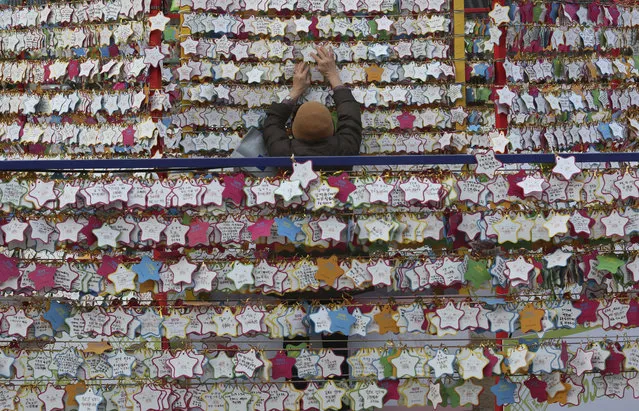 In this Monday, December 31, 2018, file photo, a woman hangs paper notes bearing her New Year wishes outside the Jogyesa Buddhist temple in Seoul, South Korea. (Photo by Ahn Young-joon/AP Photo)