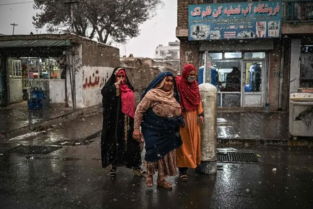 Women walk along a road during the first snow in Kabul on December 15, 2021. (Photo by Mohd Rasfan/AFP Photo)