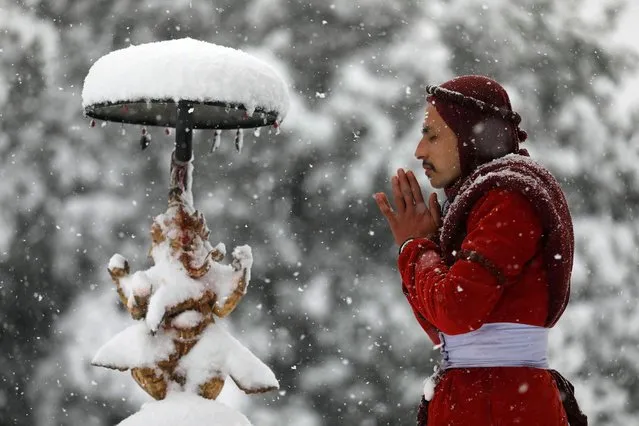 A priest offers prayers during a snowfall at the premises of Bhaleshwor Mahadev Temple in Chandragiri Hills above the Kathmandu valley, Nepal, December 29, 2021. (Photo by Navesh Chitrakar/Reuters)