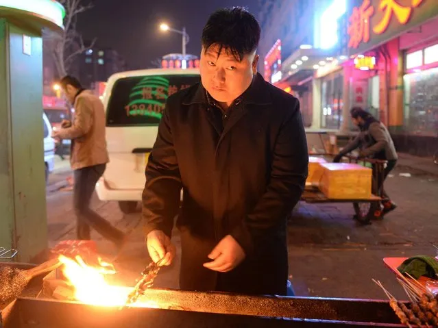 A photo made available on 25 March 2014 shows Xia, a 38-year-old kebab vendor who is dressed and looks like North Korean leader Kim Jong Un, working at his food stall in Shenyang, in northeast China's Liaoning province, on 24 March 2014. Xia's resemblance to the North Korean ruler has brought him so much business that he had to hire a helper as he is often occupied with customers taking selfies along with him. (Photo by Wei Jun/EPA)