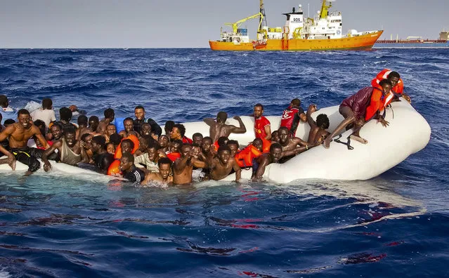 In this photo taken on Sunday, April 17, 2016 migrants ask for help from a dinghy boat as they are approached by the SOS Mediterranee's ship Aquarius, background, off the coast of the Italian island of Lampedusa. The European Union's border agency says the number of migrants crossing the Mediterranean Sea to Italy more than doubled last month. Frontex said in a statement on Monday that almost 9,600 migrants attempted the crossing, one of the most perilous sea voyages for people seeking sanctuary or jobs in Europe. (Photo by Patrick Bar/SOS Mediterranee via AP Photo)