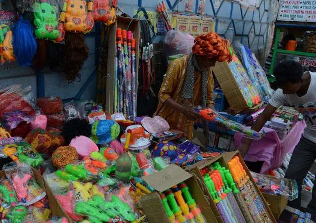 An Indian shopkeeper sells water guns at a roadside stall ahead of the Hindu festival of Holi in Siliguri on March 5, 2017. Holi, the popular Hindu spring festival of colours is observed in India at the end of the winter season on the last full moon of the lunar month and will be celebrated on March 13, this year. (Photo by Diptendu Dutta/AFP Photo)