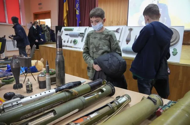 Schoolchildren look at explosives during a police-organized civilian safety lesson in a city school in Kyiv, Ukraine, Thursday, January 27, 2022. The city authorities have launches training for civilians amid fears about Russian invasion. (Photo by Efrem Lukatsky/AP Photo)