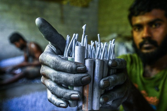 A worker makes firecrackers in the village of Kimbulapitiya on the outskirts of Colombo on April 5, 2024, ahead of the Sinhala and Tamil New Year celebrations. (Photo by Ishara S. Kodikara/AFP Photo)