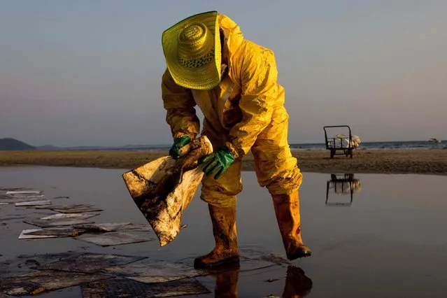 A worker cleans up crude oil on Mae Ram Phueng beach following a spill caused by a leak in an undersea pipeline owned by Star Petroleum Refining Public Company Limited (SPRC) in Rayong on January 29, 2022. (Photo by Jack Taylor/AFP Photo)