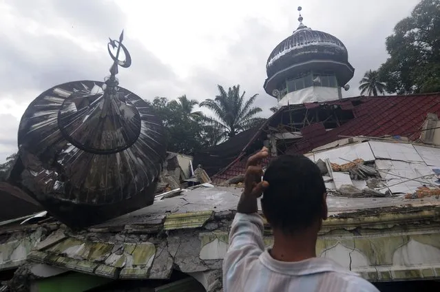 A man inspects the ruin of a damaged mosque after an earthquake in West Pasaman district, West Sumatra, Indonesia, Friday, February 25, 2022. The strong and shallow earthquake shook Sumatra on Friday, killing a number of people while causing panic on the island and in neighboring Malaysia and Singapore. (Photo by Ardhy Fernando/AP Photo)