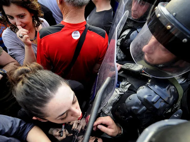 Jasmina Golubovska does her lipstick in the shield of a policeman in front of a government building in Skopje, Macedonia, on May 5, 2015. (Photo by Ognen Teofilovski/Reuters)
