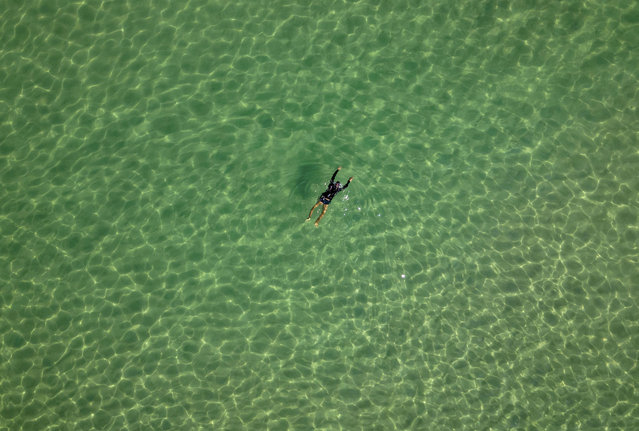 Aerial view showing a person enjoying the sea at Arpoador beach in Rio de Janeiro, Brazil, on June 21, 2024. (Photo by Florian Plaucheur/AFP Photo)