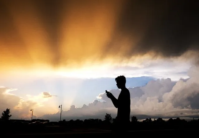 A teenager checks his cell phone as storm clouds pass Friday, July 17, 2015, in Zionsville, Ind. Scattered storms were in the forecast for most of Friday evening. (Photo by Darron Cummings/AP Photo)
