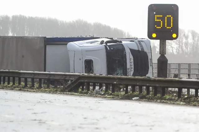 A lorry or HGV (heavy goods vehicle) lays on its side after being blown over by the wind on the M4 motorway near Margam in south Wales, on February 18, 2022 as Storm Eunice brings high winds across the country. Millions hunkered down as Storm Eunice pummelled Britain with record-breaking winds on Friday, leaving the streets of London eerily empty and disrupting flights, trains and ferries across Western Europe. (Photo by Geoff Caddick/AFP Photo)