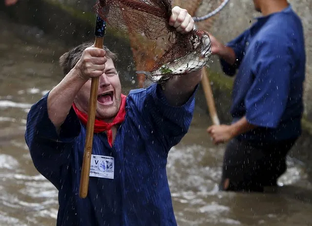 Fisherman Stefan Albrecht reacts as he catches a trout in a small river while celebrating Fischertag (Fisherman's Day) in downtown Memmingen, southern Germany, July 25, 2015. (Photo by Michaela Rehle/Reuters)