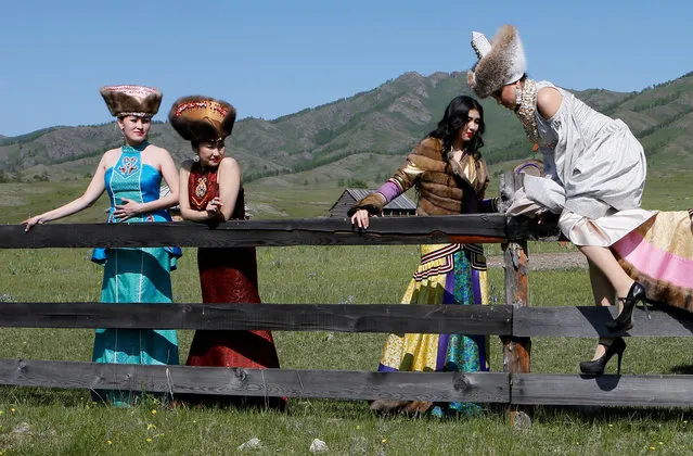 Models of the “Altyr” fashion theatre, dressed in Khakas national costumes, get over a wooden fence during a photo session, as a part of the rehearsal for the Tun-Pairam traditional holiday (The Holiday of the First Milk) celebration at a museum preserve outside Kazanovka village near Abakan in the Republic of Khakassia, Russia, May 28, 2016. (Photo by Ilya Naymushin/Reuters)