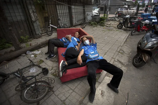 Food delivery drivers rest on an abandoned couch on a sidewalk in Beijing, Wednesday, May 24, 2017. The Moody's ratings agency on Wednesday cut China's credit rating due to surging debt, prompting a protest by Beijing and highlighting challenges faced by communist leaders as they overhaul a slowing economy. (Photo by Mark Schiefelbein/AP Photo)