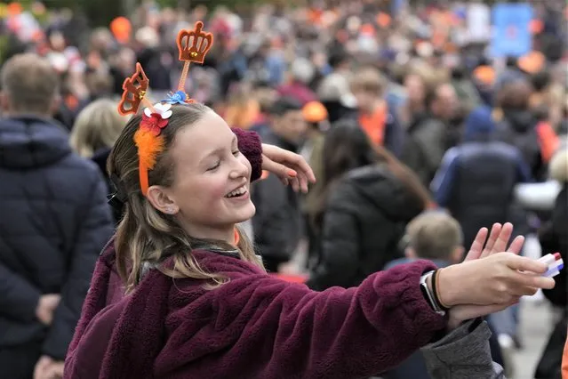A girl jokes with a friend as they offer to decorate faces in the red-white-blue colors of the national flag during King's Day celebrations in Amsterdam, Netherlands, Wednesday, April 27, 2022. After two years of celebrations muted by coronavirus lockdowns, the Netherlands marked the 55th anniversary of King Willem-Alexander with street parties, music festivals and a national poll showing trust in the monarch ebbing away. (Photo by Peter Dejong/AP Photo)